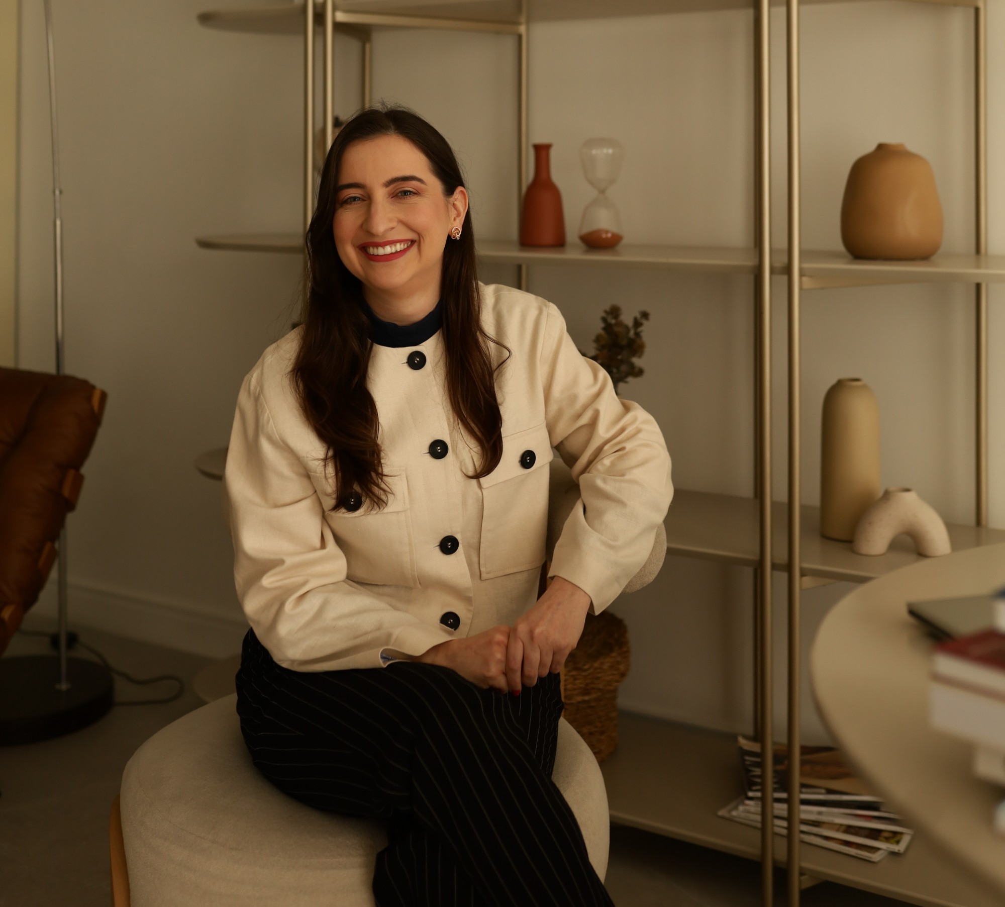 Dra. Maria Clara Piraciaba sorrindo, sentada em um consultório acolhedor