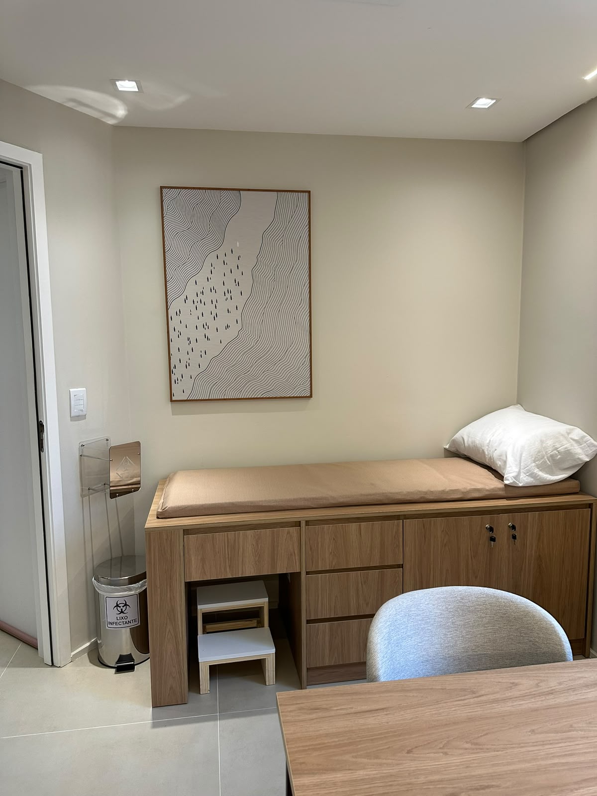 Sala de exame com maca revestida e quadro na parede